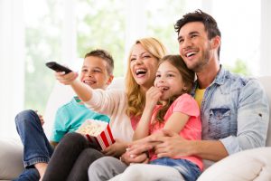 Happy family watching TV and eating popcorn